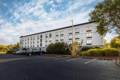 un gran edificio blanco con coches aparcados en un aparcamiento en Wingate by Wyndham Charlotte Concord Mills/Speedway, en Concord