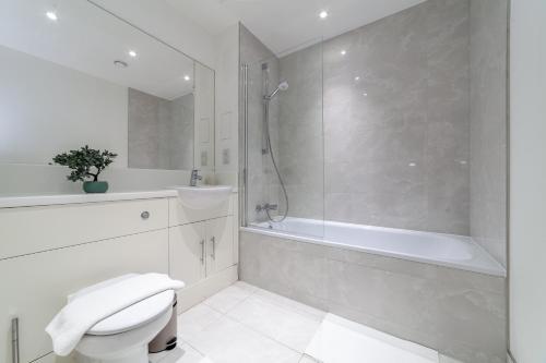 uma casa de banho branca com um chuveiro, um WC e uma banheira em The Wandsworth Luxury Studio em Londres