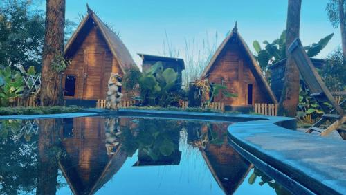 a couple of cottages are reflected in the water at Triangle House and hot spring in Kintamani