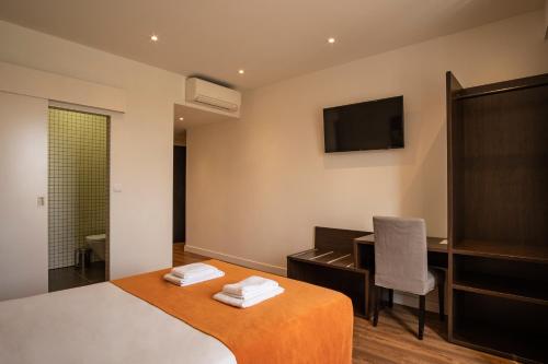 a bedroom with a bed and a desk and a television at Riversuites in Coimbra