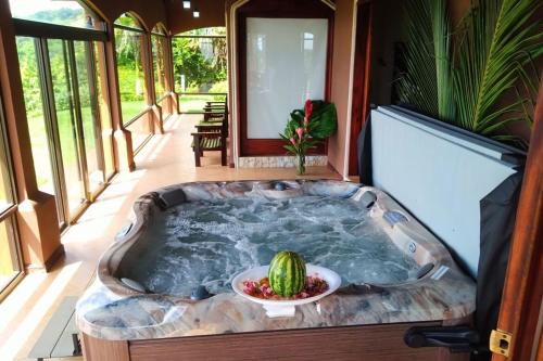a jacuzzi tub with a bowl of watermelon in the middle at Luxury Spa Dream Villa At Lake Arenal in Tilarán