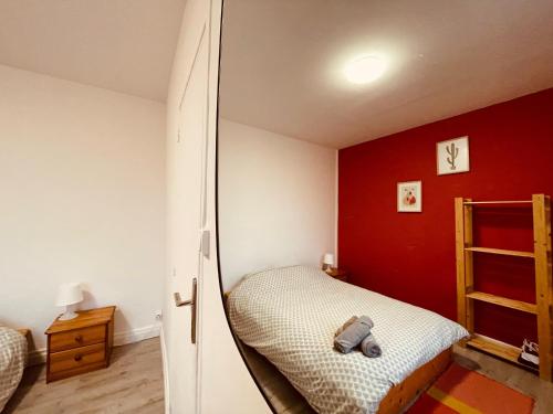 um quarto com uma cama com uma parede vermelha em L'appartement Des montagnes de couleur-286 em Saint-Étienne-du-Rouvray