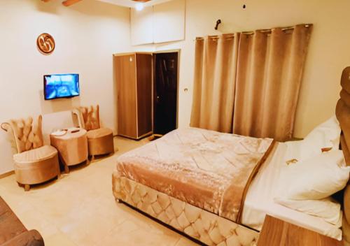 sypialnia z łóżkiem, krzesłami i telewizorem w obiekcie Hotel Day In Emporium w mieście Lahaur