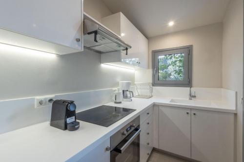uma cozinha com balcões brancos, um lavatório e uma janela em Vineyard Estate em Porto Heli