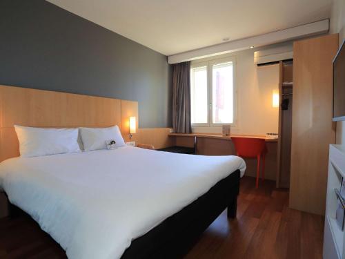 オーリヤックにあるibis Aurillacの大きなベッドとデスクが備わるホテルルームです。