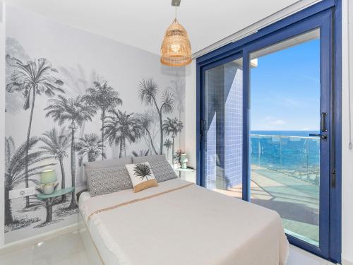 Schlafzimmer mit einem Bett mit Palmen an der Wand in der Unterkunft Luxury Penthouse with a Private Jacuzzi! in Punta Prima