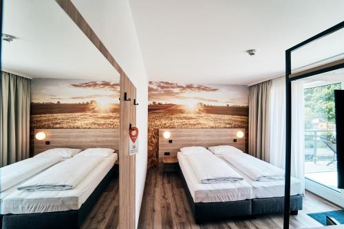 two beds in a room with a painting on the wall at I'M INN Zwettl - Hotel zum Brauhaus in Zwettl Stadt