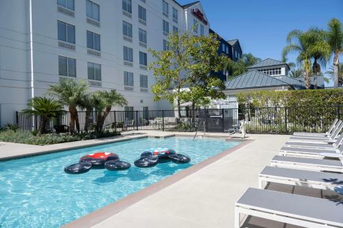 an indoor swimming pool with inflatable tubes in a building at Hilton Garden Inn Anaheim/Garden Grove in Anaheim