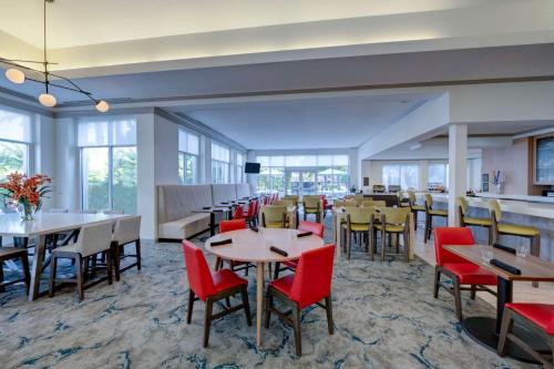 Un comedor con mesas y sillas y ventanas. en Hilton Garden Inn Anaheim/Garden Grove, en Anaheim