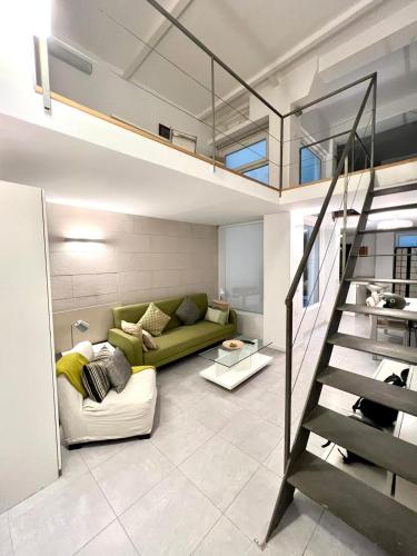 a living room with a green couch and a staircase at Excelente loft en Trafalgar in Madrid