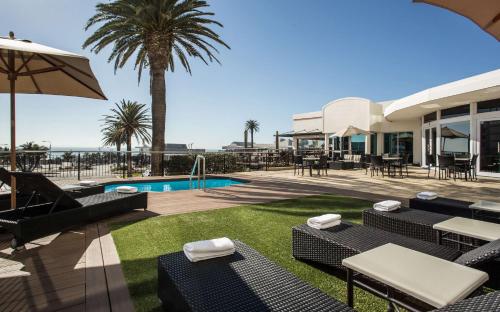 a patio with chairs and a pool and a house at Garden Court Kings Beach in Port Elizabeth