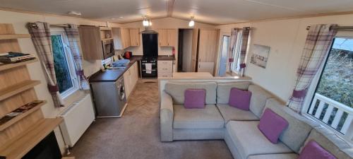 a living room with a couch and purple pillows at Holiday Caravan at Beauport in Hastings