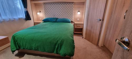 een kleine slaapkamer met een bed met een groen dekbed bij Holiday Caravan at Beauport in Hastings