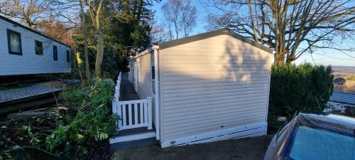 a small white shed next to a house at Holiday Caravan at Beauport in Hastings