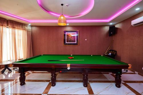 a pool table in a room with pink lighting at Vintano Hotel in Lekki