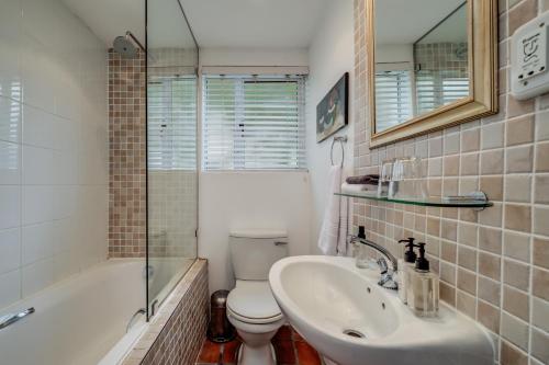 a bathroom with a sink and a toilet and a shower at Camps Bay Terrace Palm Suite in Cape Town