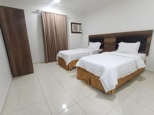 um quarto de hotel com duas camas com lençóis brancos em شقق مفروشة شهري وسنوي em Obhor