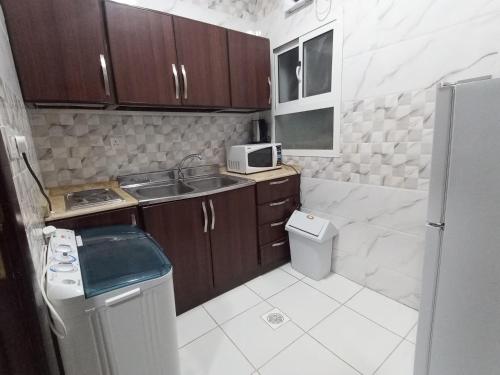 uma pequena cozinha com um lavatório e um micro-ondas em شقق مفروشة شهري وسنوي em Obhor
