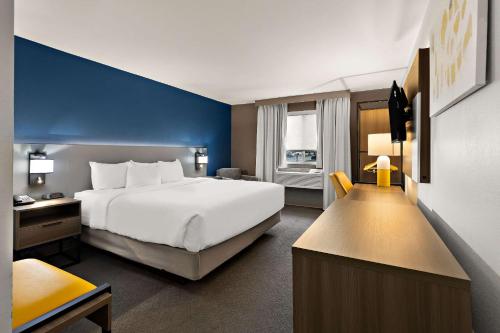 Comfort Inn & Suites في فريمونت: غرفة فندق بسرير ابيض وجدار ازرق