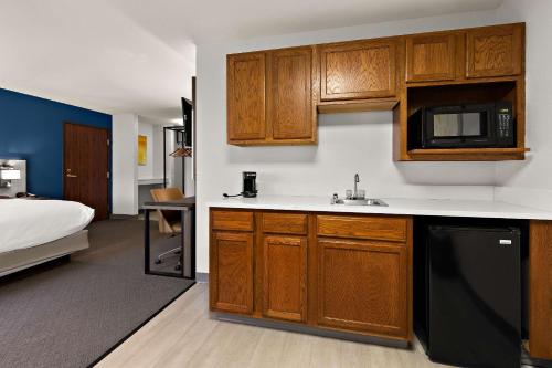 una cocina con armarios de madera y una cama en una habitación en Comfort Inn & Suites, en Fremont