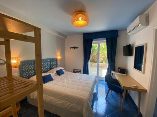 a bedroom with a bed and a desk and a window at Hotel Villa Lubrense Sorrento in Massa Lubrense