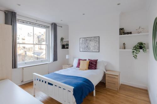 Habitación blanca con cama y ventana en So Glamorous Pad - Fitzrovia - by Frankie Says, en Londres