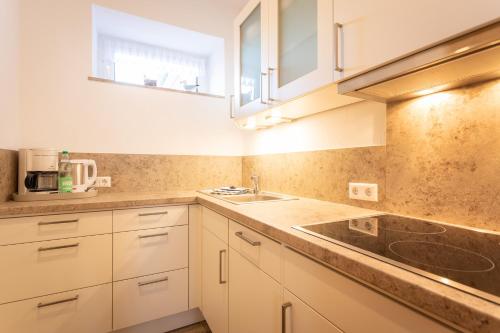 a kitchen with white cabinets and a sink at Sanddornhaus in Norderney