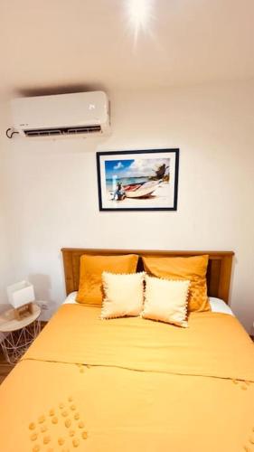 a bedroom with a yellow bed with two pillows at Studio Bis Océan 2 personnes Sainte-Anne plage in Sainte-Anne