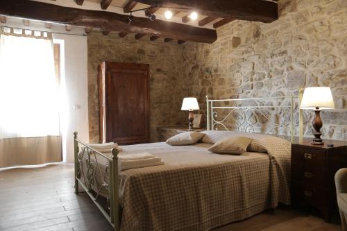 1 dormitorio con cama y pared de piedra en Agriturismo Podere Acqualoreto, en Acqualoreto