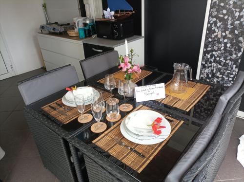 - une table avec des assiettes et des verres à vin dans l'établissement TI KAZ PIROGUE, à Étang-Salé les Bains