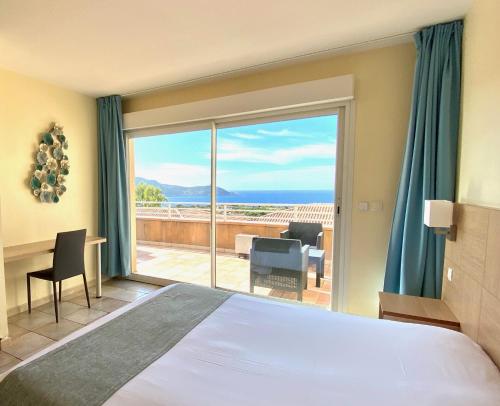 a bedroom with a bed and a large window with a view at CALVI APPART HÔTEL in Calvi