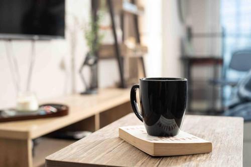 a black coffee cup sitting on a coaster on a table at Cozy 1BR with Balcony and Netflix in Uptown BGC in Manila