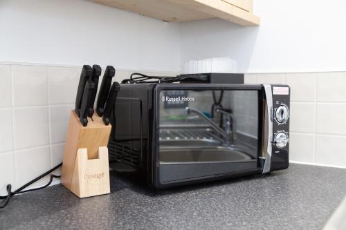 a black toaster oven sitting on a counter with knives at Serviced Apartment in Liverpool City Centre - Free Parking - Balcony - by Happy Days in Liverpool