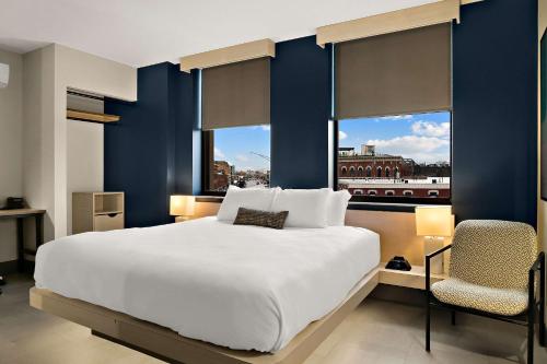 Un dormitorio con una gran cama blanca y una ventana en CityFlatsHotel - Port Huron, Ascend Hotel Collection, en Port Huron