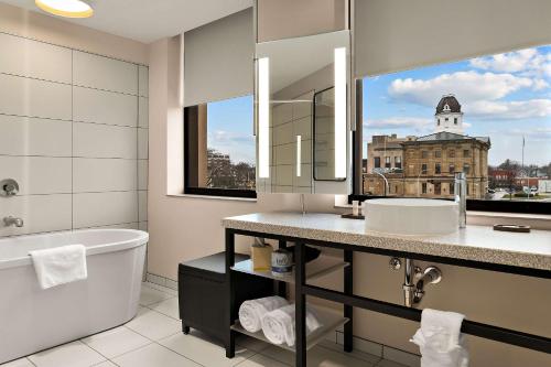 a bathroom with a tub and a sink and a mirror at CityFlatsHotel - Port Huron, Ascend Hotel Collection in Port Huron