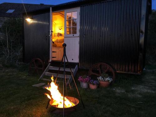 una hoguera frente a una casa pequeña en shepherd hut glamping in Northumberland en Newcastle