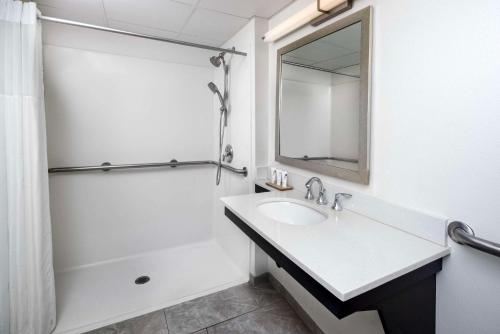 Baño blanco con lavabo y espejo en Country Inn & Suites by Radisson Asheville Downtown Tunnel Road, en Asheville