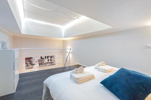 Un dormitorio con una cama blanca con toallas. en Exclusive Loft - Life is Beautiful - Free WiFi - 5 min To Metro Nizza, en Turín