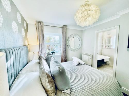 a bedroom with a bed with pillows and a chandelier at Cotswold Chic Retreats "Jacinabox" 5 Star Chipping Campden-Parking-Garden in Chipping Campden