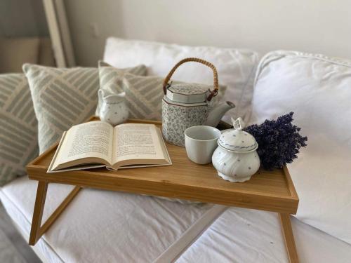 a tray with an open book on a bed with cups and tea pots at Somlói Provence in Doba