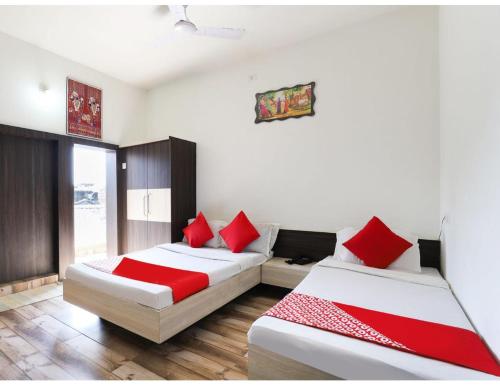 two beds in a room with red pillows at HOTEL MADHUVAN, Madhavpur in Mādhavpur