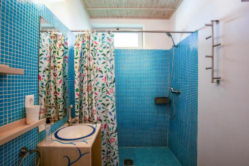 uma casa de banho em azulejos azuis com um chuveiro e um lavatório. em Surfers Spot em Ponta do Ouro