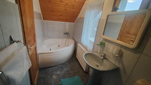 a bathroom with a tub and a sink and a bath tub at Casa Ciubărului Bran in Predeluţ
