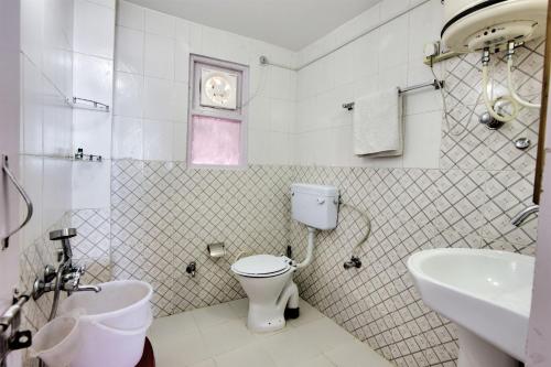 a white bathroom with a toilet and a sink at Agro Stone Cottage & Cafe in Mashobra