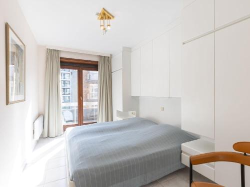 une chambre blanche avec un lit et une fenêtre dans l'établissement Cosy apartment with living room, à Middelkerke