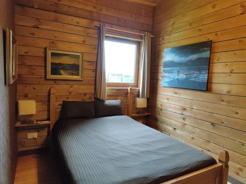 um quarto com uma cama num quarto de madeira em Holiday House with garden and sauna em Durness