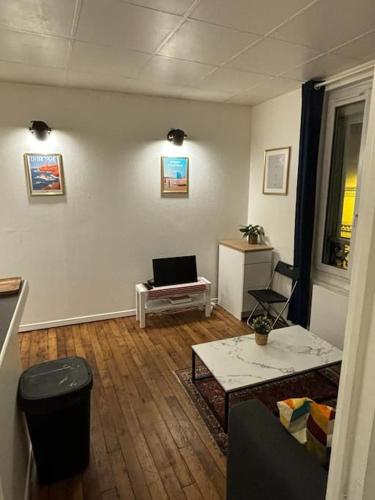 a living room with a table and a laptop in it at Appartement cosy proche métro in Ivry-sur-Seine