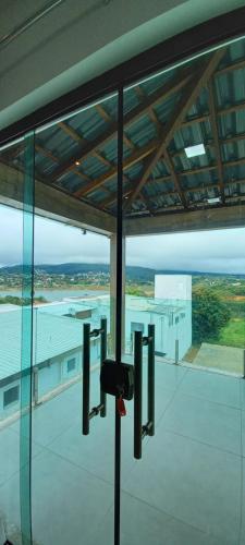 - une vue sur un bâtiment depuis l'intérieur d'un bâtiment en verre dans l'établissement RECANTO BRENDA - Casa Luxo Capitólio com Vista pro lago, Escarpas e MorroChapeu, à Capitólio