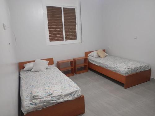 Zimmer mit 2 Betten und einem Fenster in der Unterkunft Alhoceima Ville Appartement in Al Hoceïma