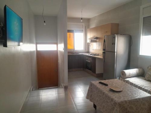 eine Küche mit einem Kühlschrank und einem Tisch im Zimmer in der Unterkunft Alhoceima Ville Appartement in Al Hoceïma